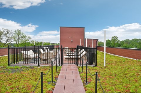 A red building with a black fence and a walkway leading to it.