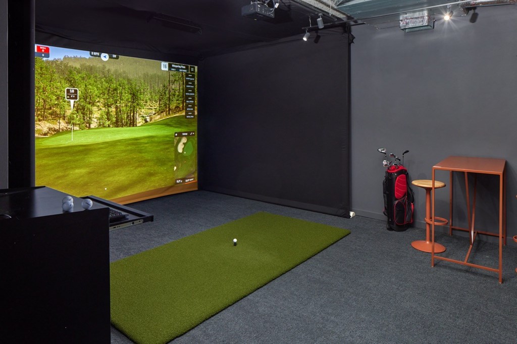 A golf simulator room with a screen and a mat.