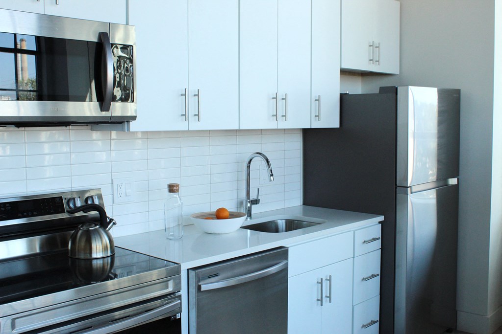 a white kitchen with stainless steel appliances and white cabinets