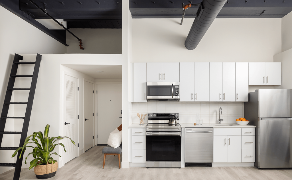 a kitchen with white cabinets and stainless steel appliances and a black staircase