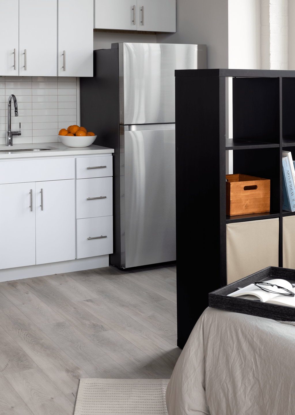 a kitchen with white cabinets and stainless steel appliances and a bed