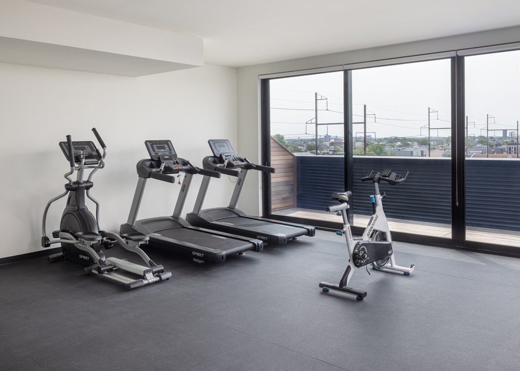 two treadmills and elliptical machines in a fitness room with a view of the city