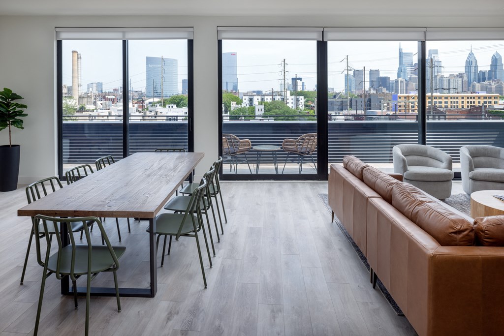 a communal area with a wooden table and chairs and a large window with a view of the