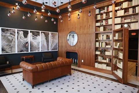 A living room with a brown leather couch and a fireplace.