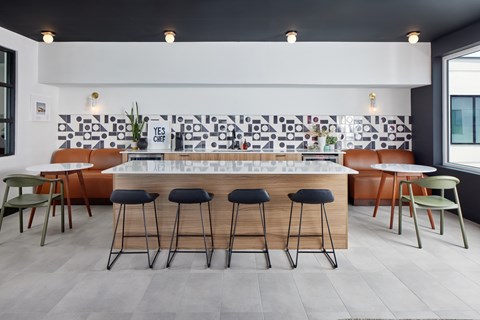 A modern bar area with a white counter and black stools. at The Weaver, Philadelphia, PA, 19125