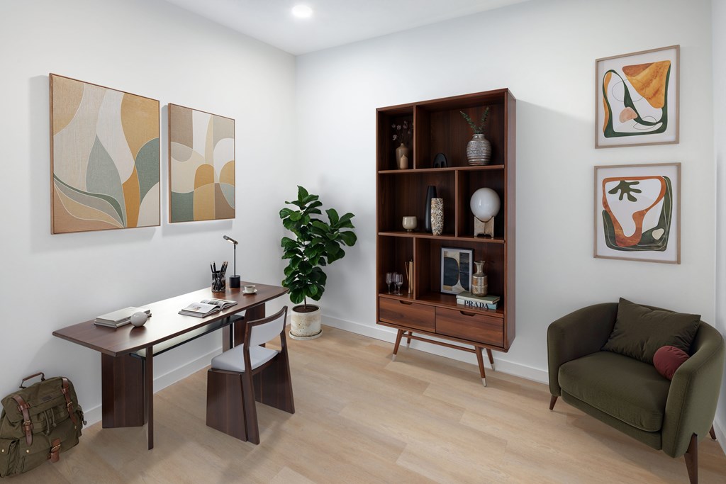 A room with a desk, chair, and a bookshelf with various items on it.