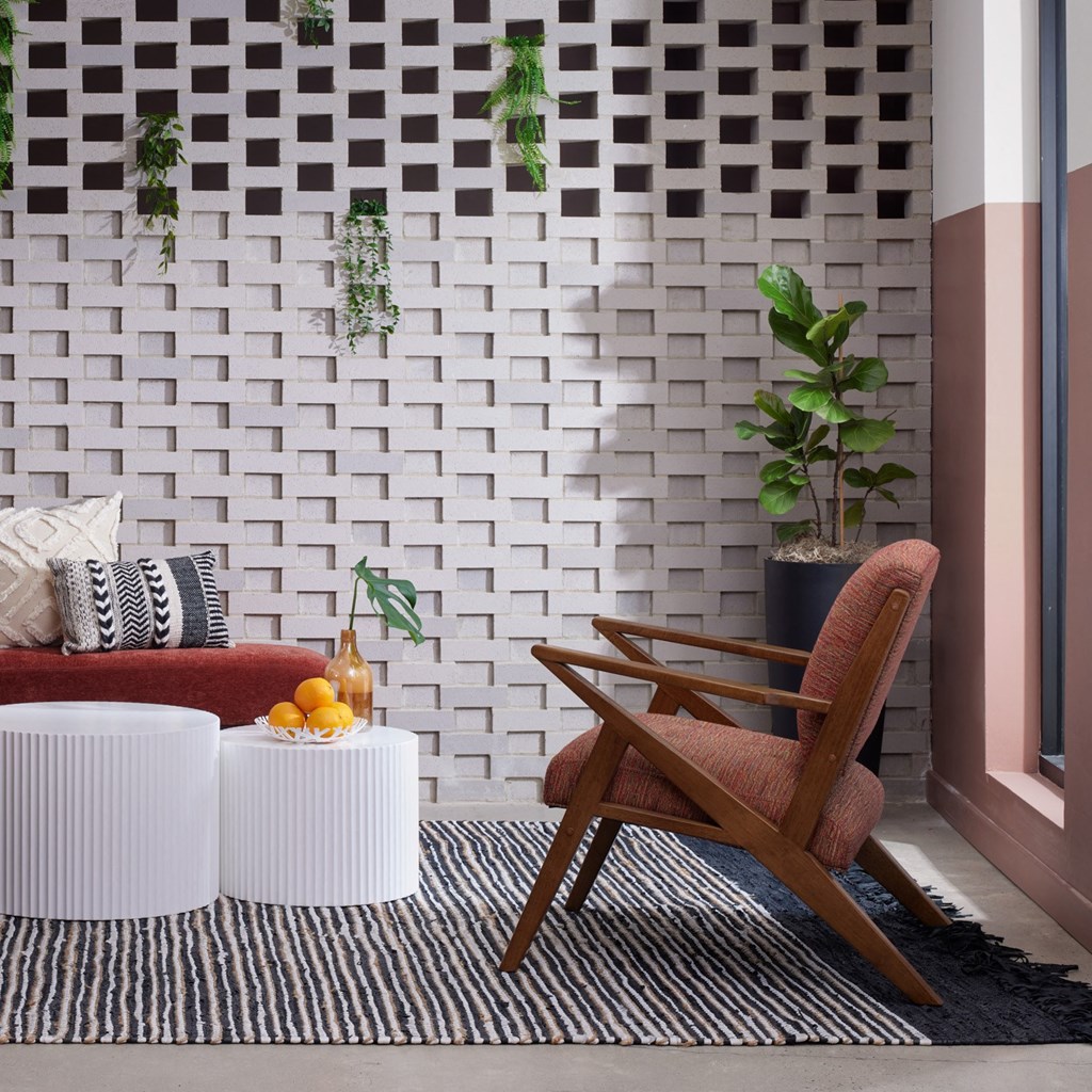 a living room with a chair and a couch and a striped rug