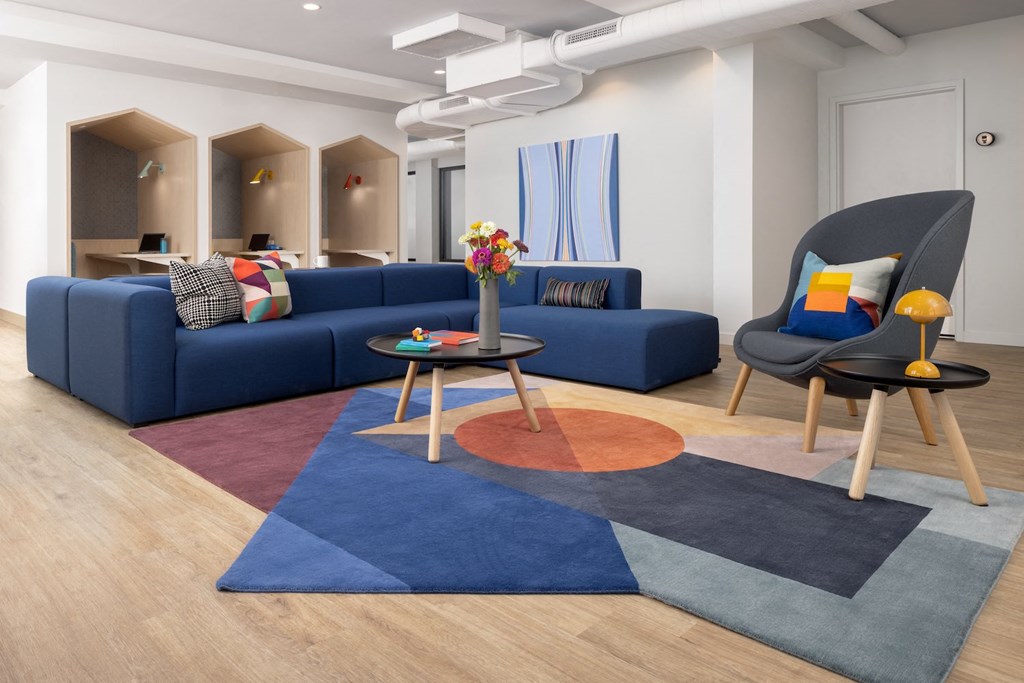 a living room with blue couches and chairs and a rug