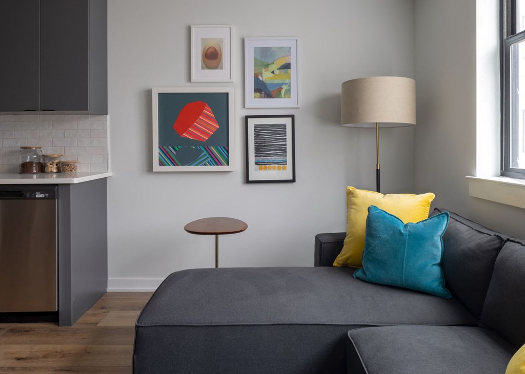 a living room with a couch and a lamp and pictures on the wall
