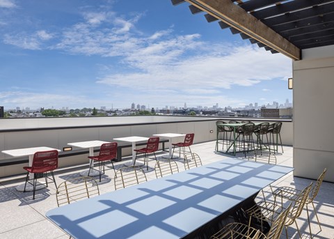 A patio with tables and chairs overlooking a city skyline. at The Weaver, Philadelphia, PA, 19125