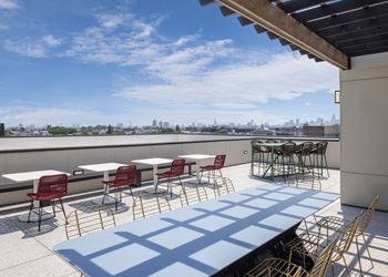 A patio with tables and chairs overlooking a city skyline. at The Weaver, Philadelphia, PA, 19125