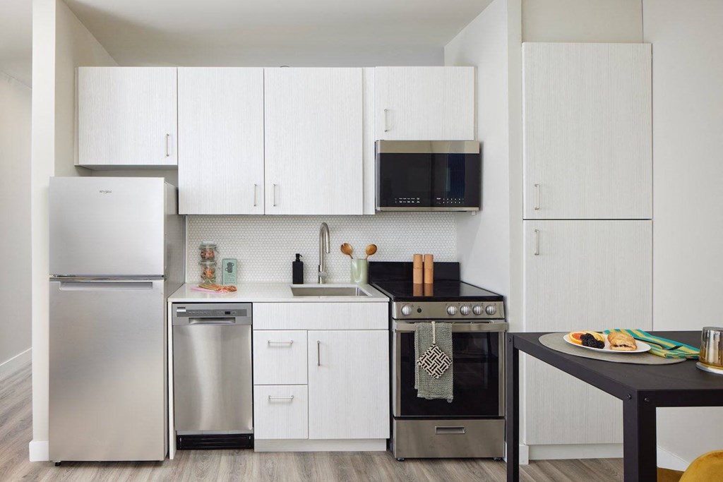 a white kitchen with stainless steel appliances and a black table