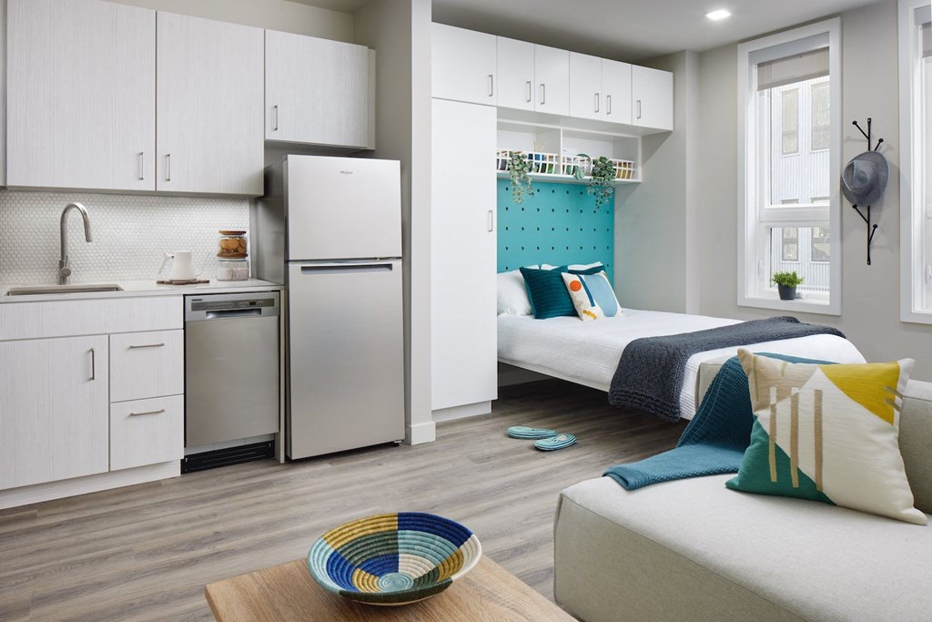 a studio apartment with two beds and a refrigerator and a sink