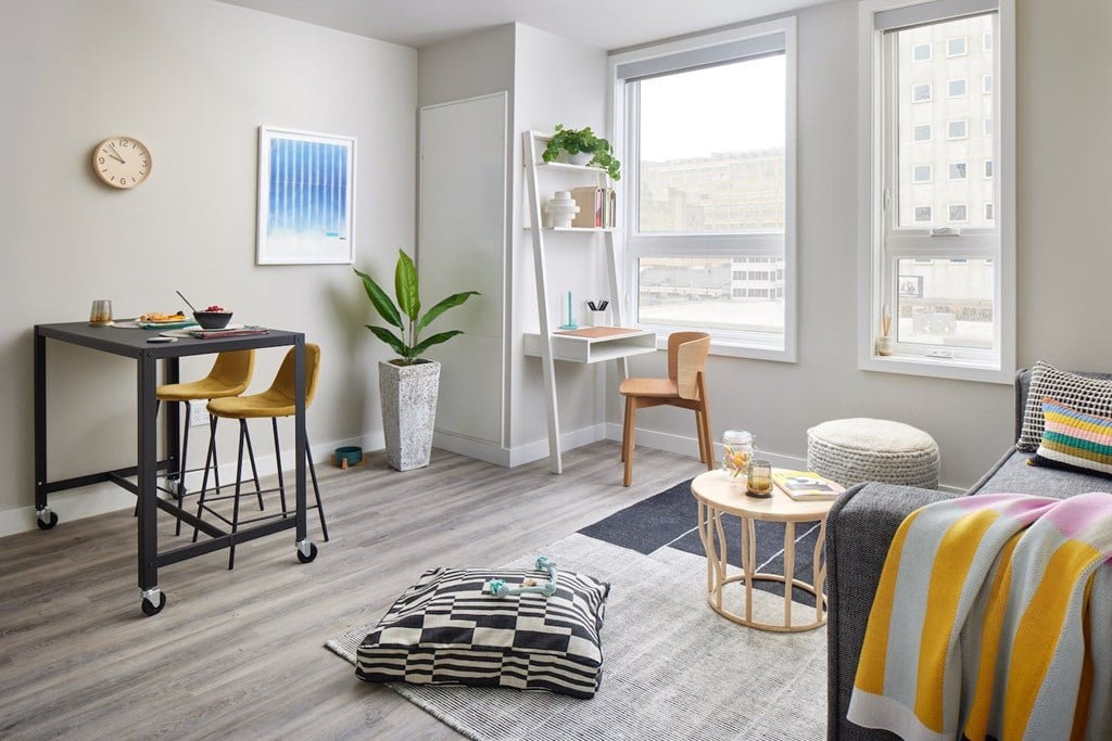 a living room with a desk and a window     and a bed
