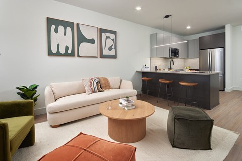 A modern living room with a white couch, a wooden coffee table, and a kitchen area in the background. at Glassworks, Philadelphia, Pennsylvania