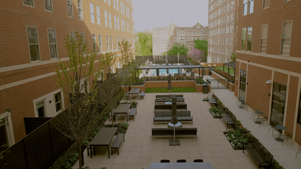 A courtyard with benches and a table surrounded by buildings.