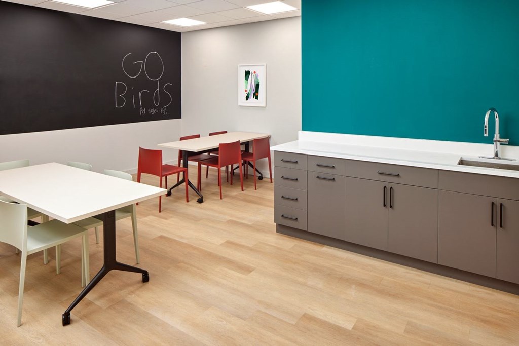 A room with a white table and chairs and a blackboard with the words "GO BIRDS" written on it.