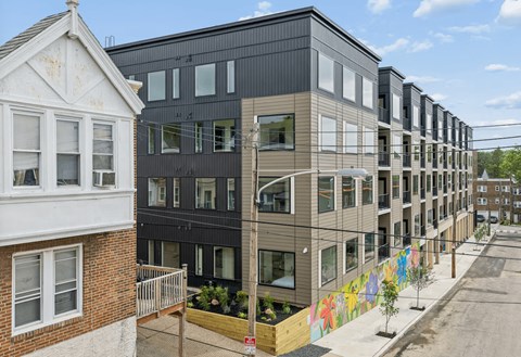 A row of modern townhouses with a colorful mural on the side.