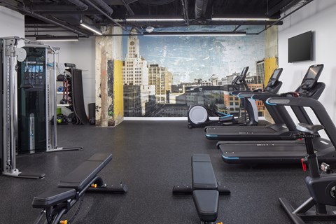 A gym with treadmills, weights, and a city view mural on the wall.at 1600 Callowhill, Philadelphia, PA