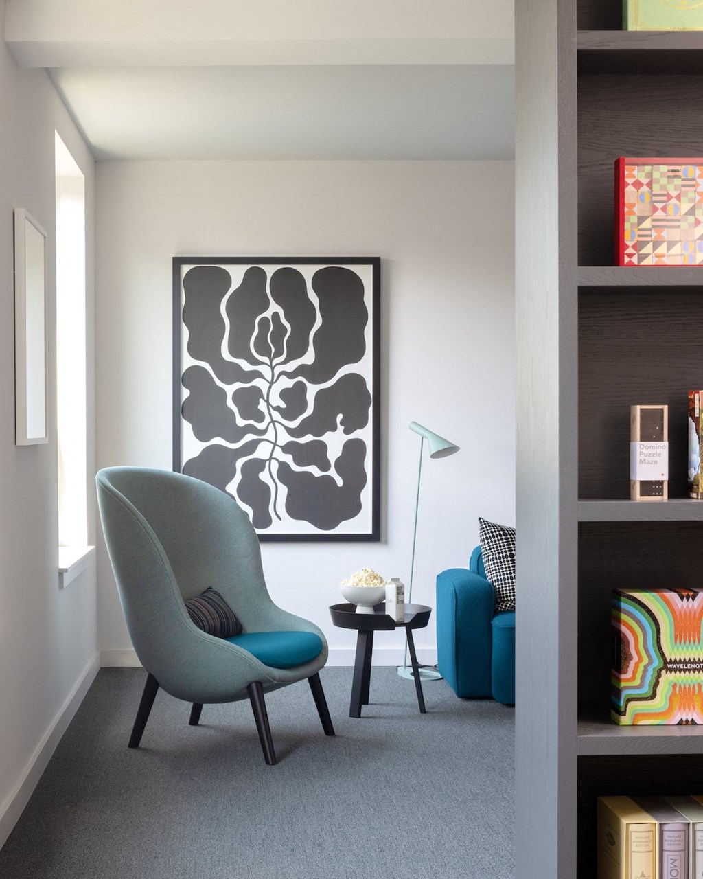 a living room with a chair and a table and a painting on the wall