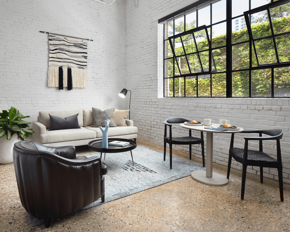 a living room with a couch and tables and a large window