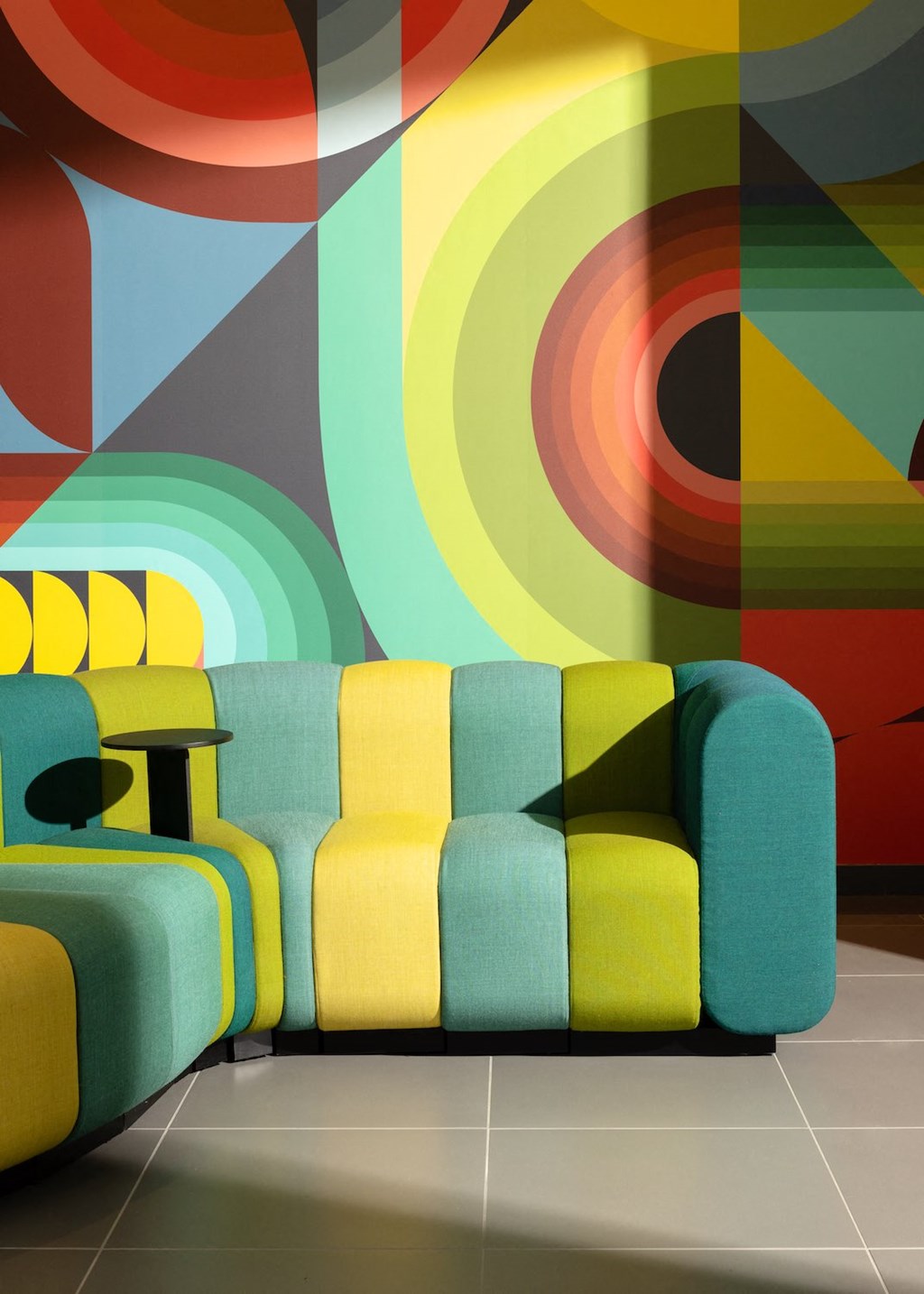 a living room with a couch and chair against a colorful wall
