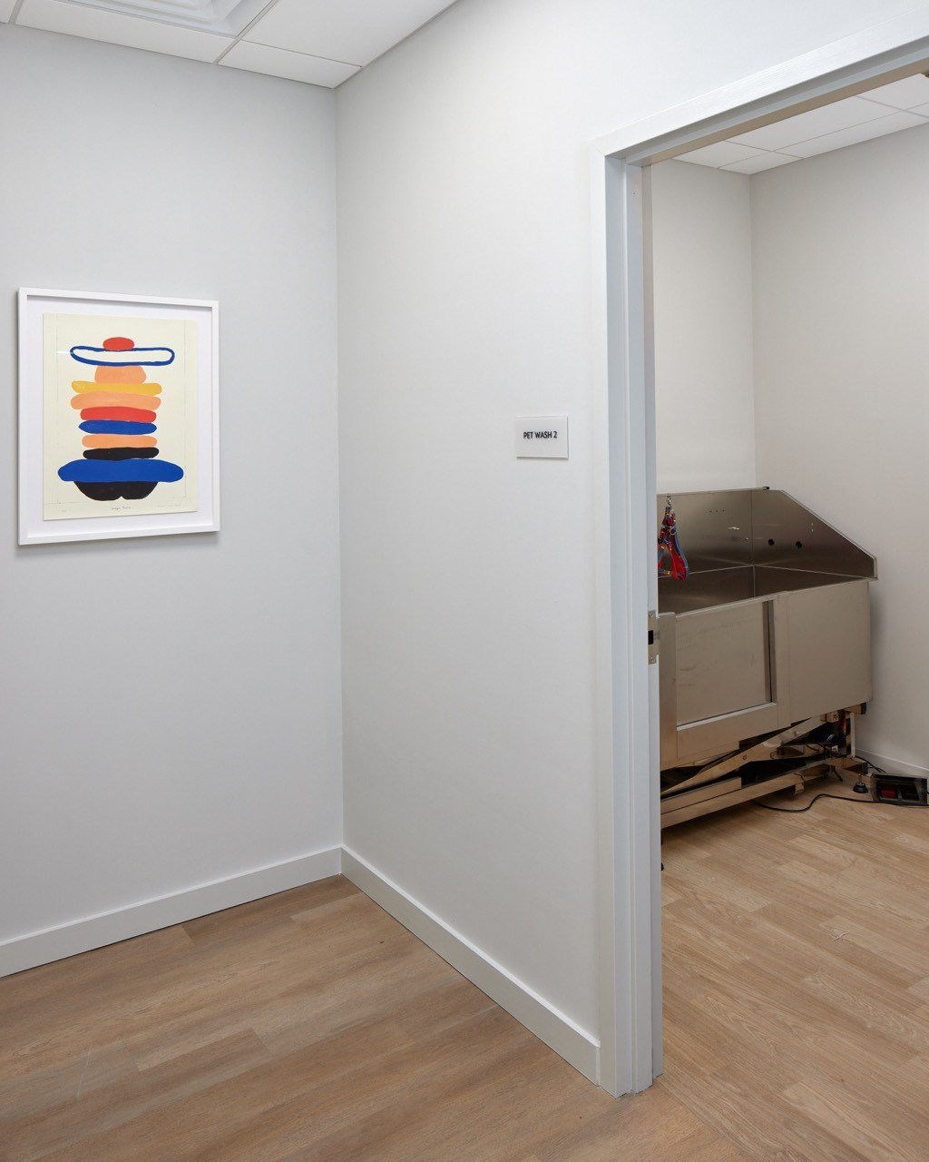 A painting of a stack of shapes is on the wall in a white room.