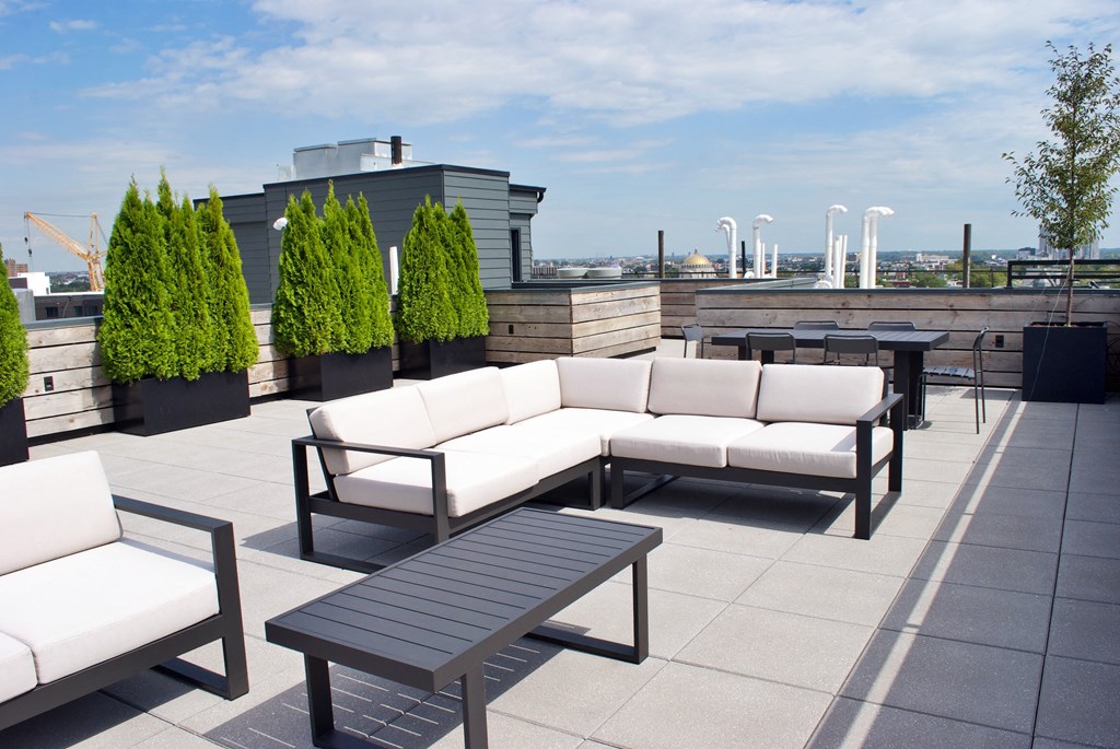 a roof top patio with couches and tables and plants