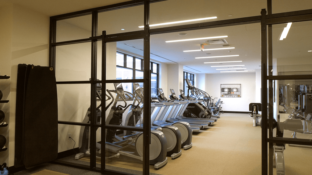 A gym with a row of treadmills and a row of stationary bikes.