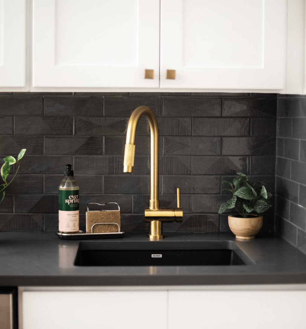 a kitchen sink with a gold faucet and white cabinets