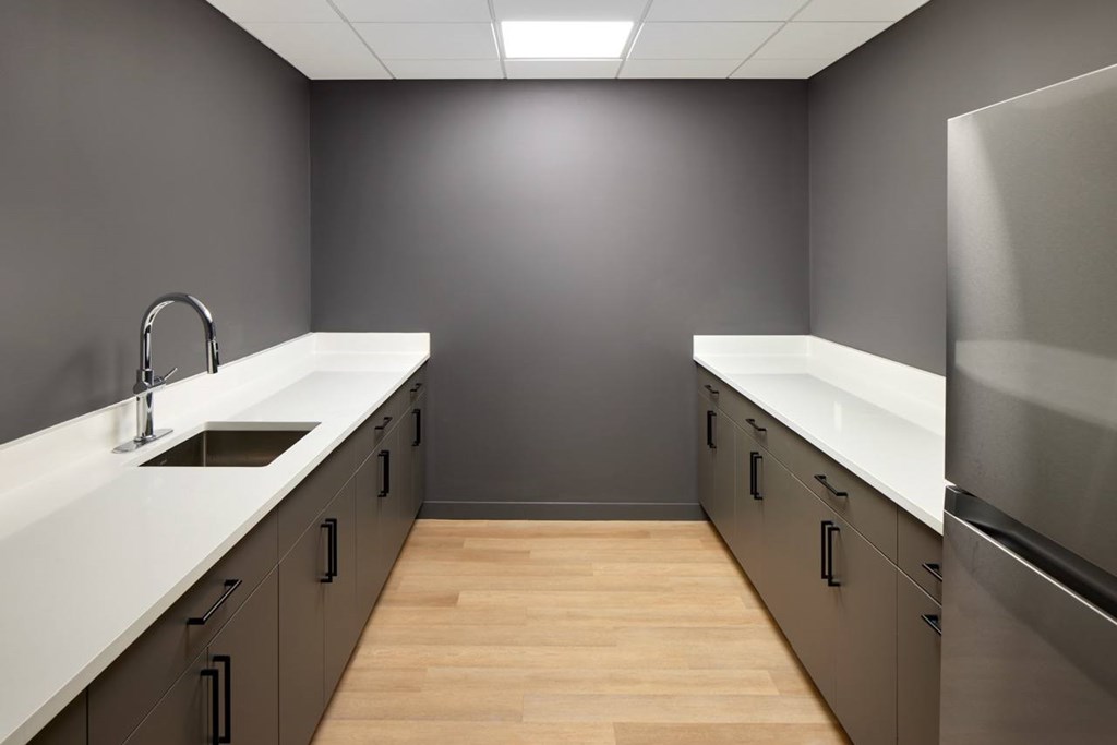 A kitchen with a white counter top and wooden floors.