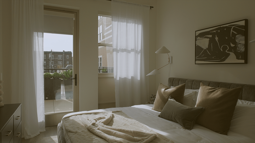 A bedroom with a bed, pillows, and a painting on the wall.