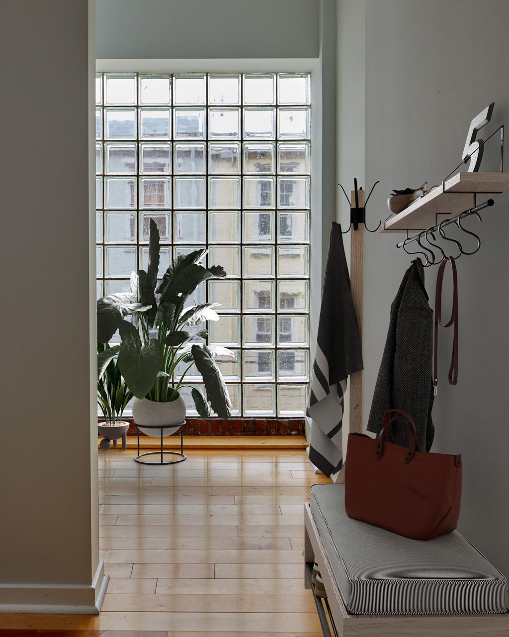 a living room with a large window and a bench with a bag and a plant
