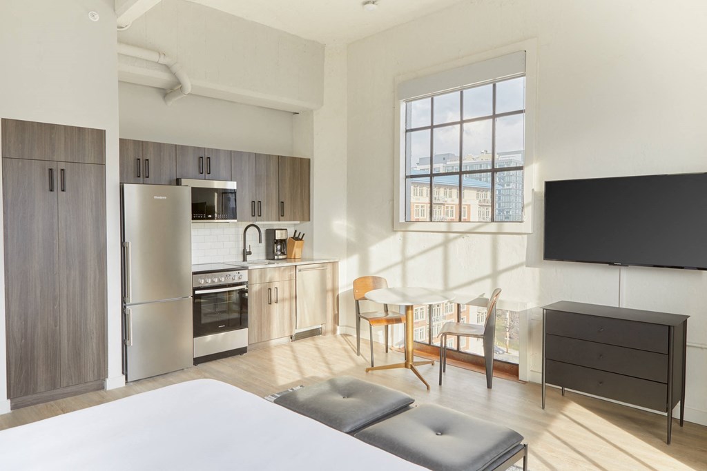 a studio apartment with a kitchen and a bed and a table and chairs