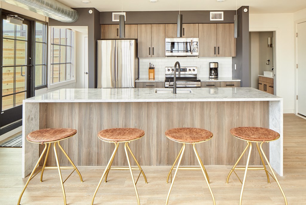 a kitchen with three stools in front of a counter top