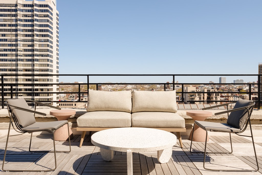 a furnished patio with a couch and tables on a balcony