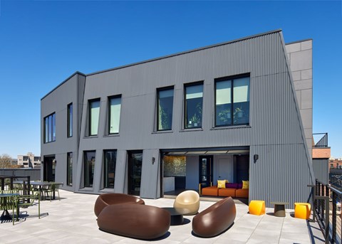 A modern building with a grey exterior and a patio with bean bag chairs.