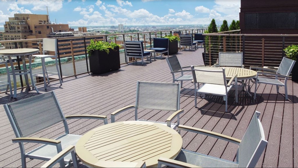 a roof top patio with tables and chairs and a view of the city