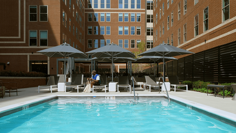Outdoor pool with umbrellas and lounge chairs at Garden Court Towers Apartments, Philadelphia, PA 19143