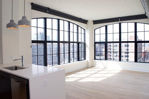 a view of a living room with large windows and a kitchen