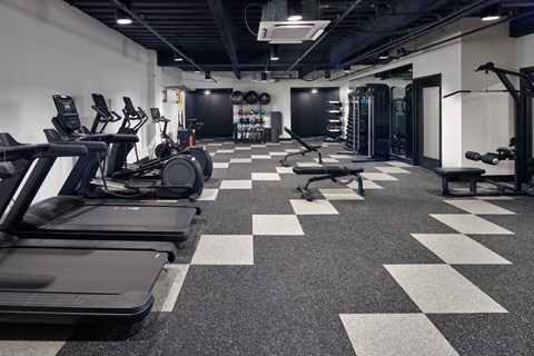 A gym with treadmills, weights, and a checkerboard floor.