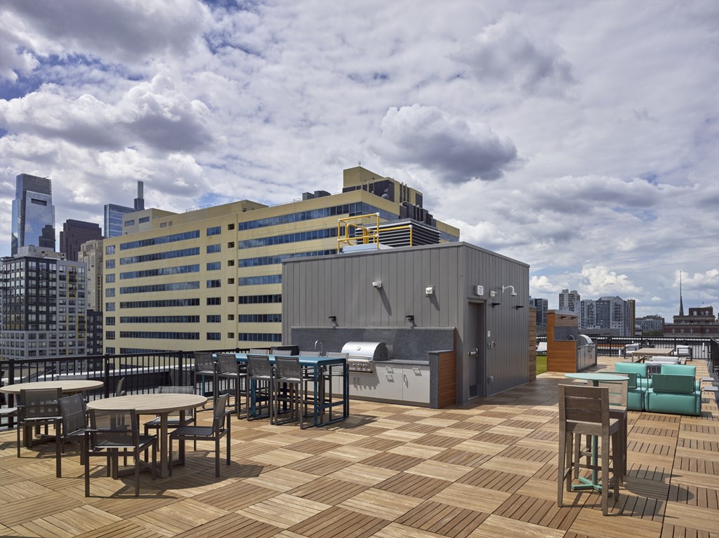a rooftop patio with tables and chairs and a city in the background