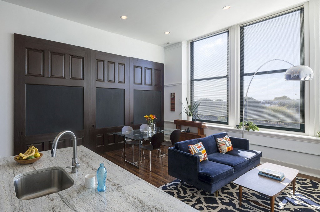 a living room with a couch and a kitchen with a sink