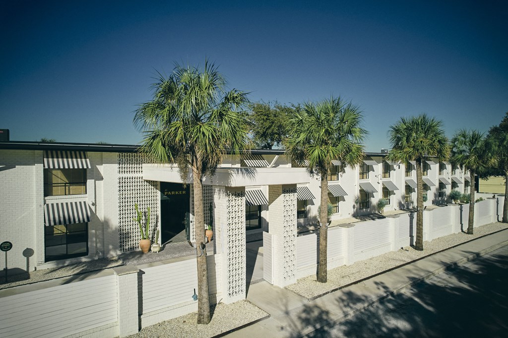 A row of white buildings with palm trees in front at The PARKER on E Mulberry Apartments, San Antonio, TX