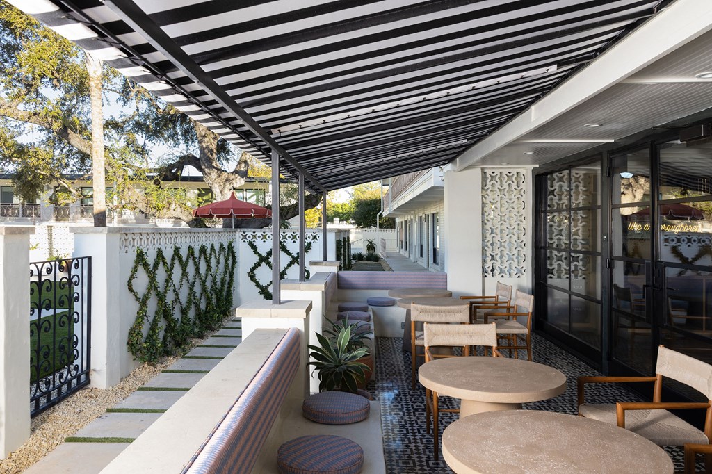 A patio with a black and white striped awning and a table with chairs at The PARKER on E Mulberry Apartments, San Antonio