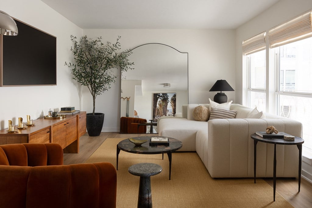 A living room with a white couch, a brown armchair, and a coffee table at The PARKER on E Mulberry Apartments, San Antonio, TX