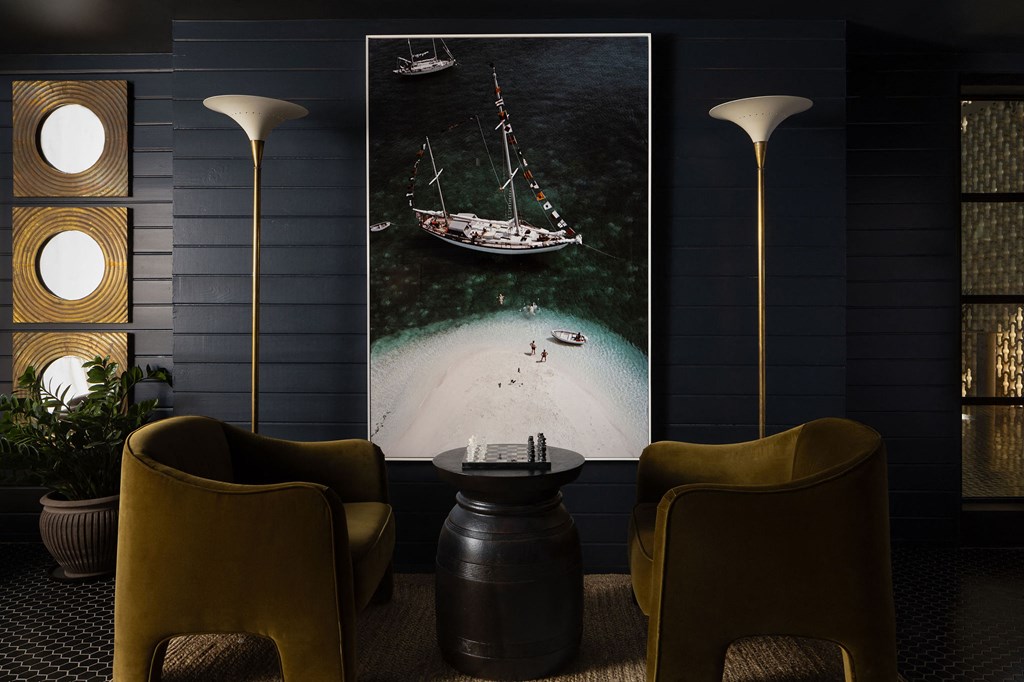 A room with a large picture of a boat on the wall and two yellow chairs at The PARKER on E Mulberry Apartments, San Antonio, Texas