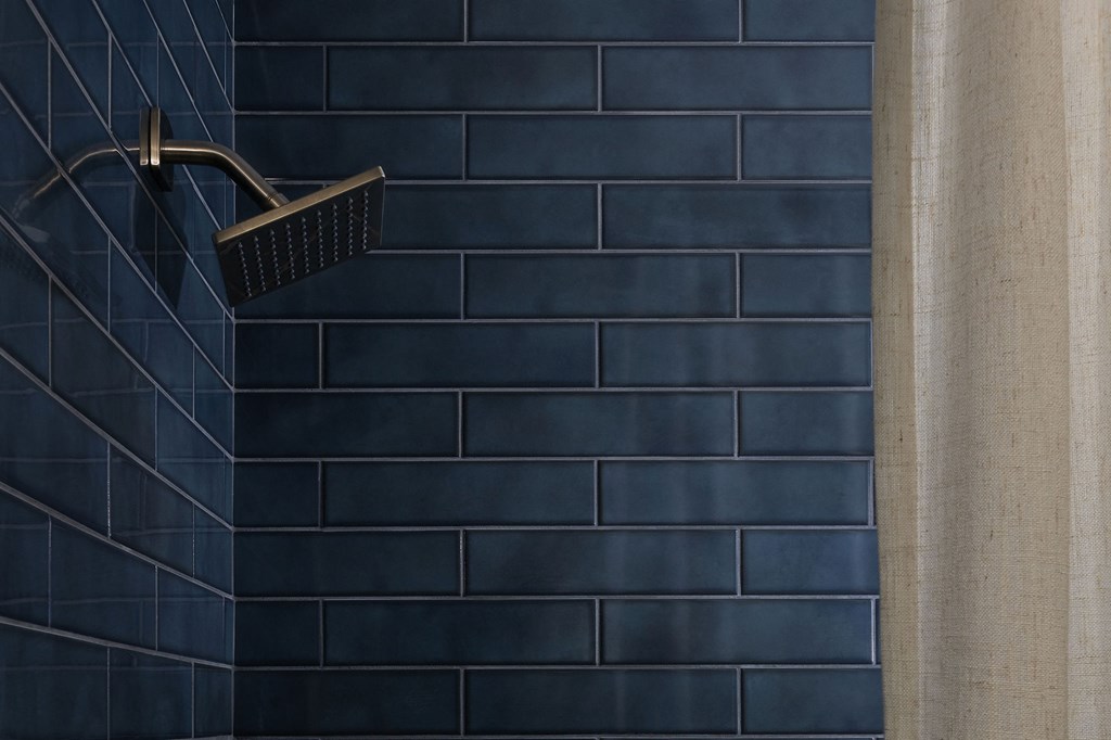 A black shower head mounted on a wall at The PARKER on E Mulberry Apartments, Texas