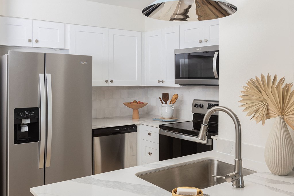 A modern kitchen with a stainless steel refrigerator and a white countertop at The PARKER on E Mulberry Apartments, San Antonio, Texas