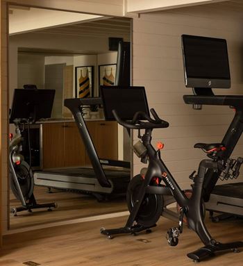 A room with a treadmill, a stationary bike and a computer monitor.
